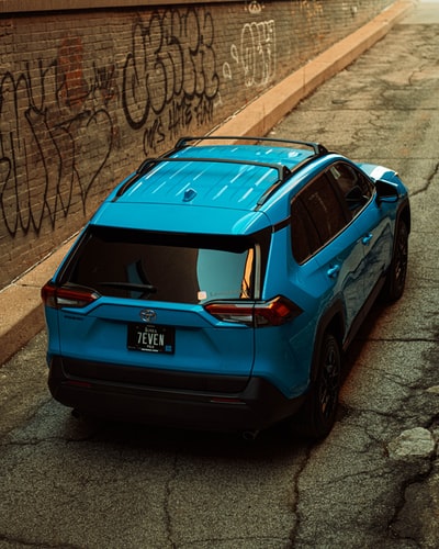 blue honda car parked beside brown brick wall